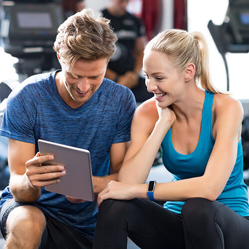 Sportliches Paar schaut sich auf dem Tablet die Angebote der Aktivwoche an